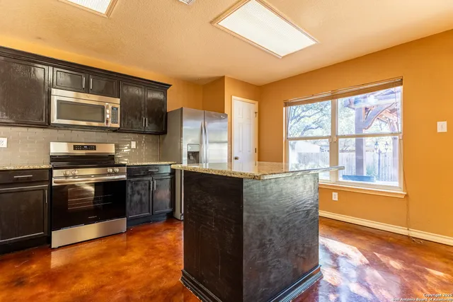 a kitchen with stainless steel appliances granite countertop a stove a sink and a microwave
