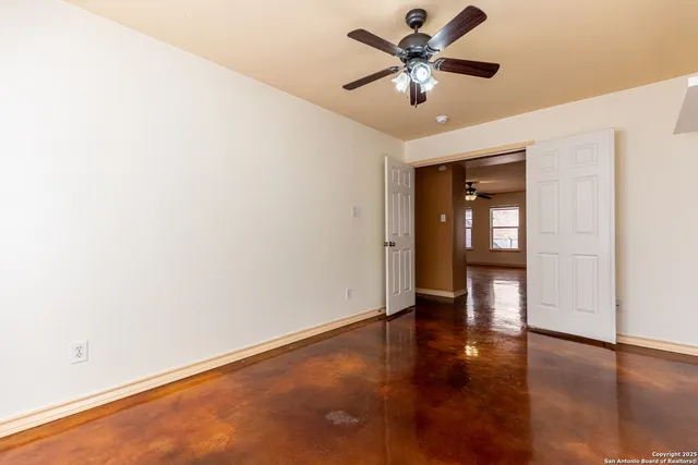 a view of an empty room with window and wooden floor