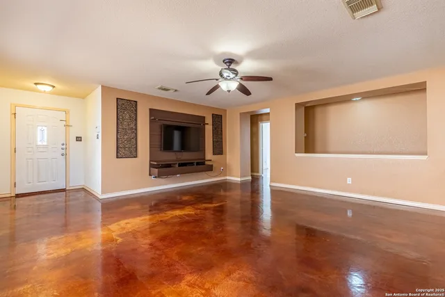 a view of a livingroom with a flat screen tv wooden floor and a ceiling fan
