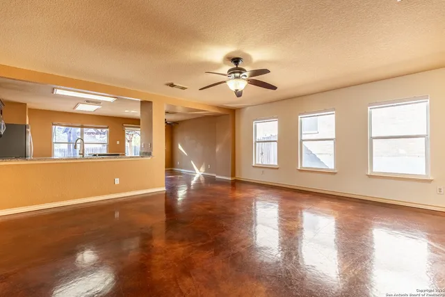 a view of an empty room with window and wooden floor