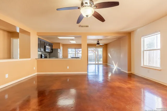 a view of an empty room with window and wooden floor