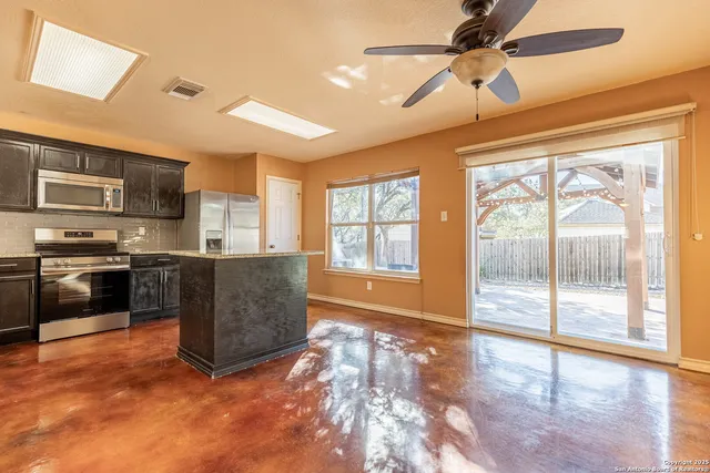 a kitchen with stainless steel appliances granite countertop a stove top oven a sink a dining table and chairs with wooden floor