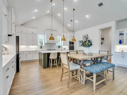 a kitchen with stainless steel appliances kitchen island granite countertop a table chairs sink and cabinets