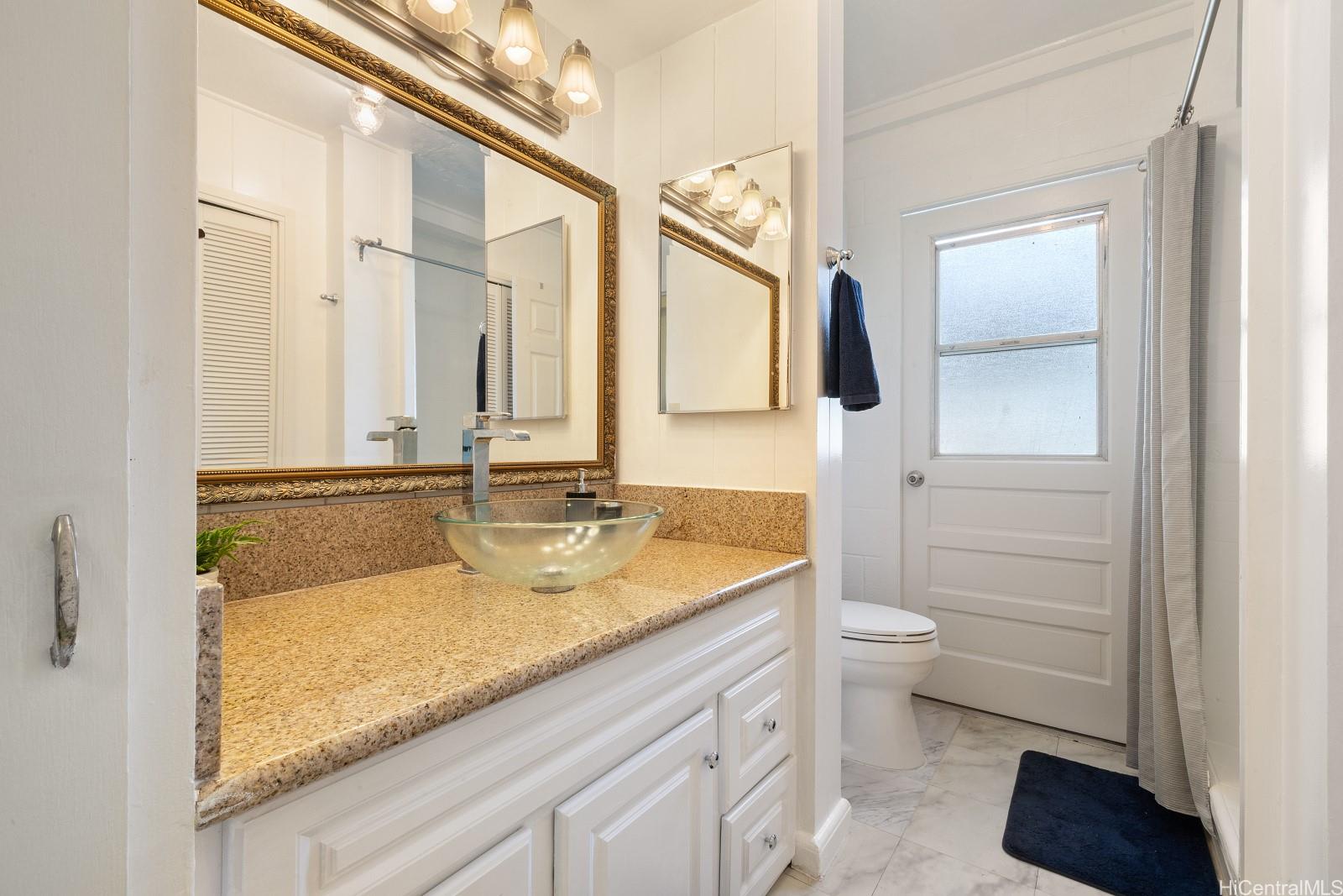 240 Puiwa Road Honolulu, HI 96817 - Photo 16 of 18 a bathroom with a granite countertop sink a toilet and a mirror