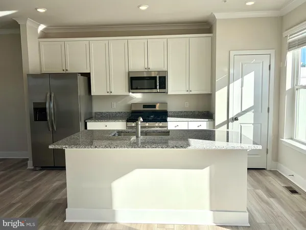 a kitchen with stainless steel appliances granite countertop a sink a microwave a refrigerator and white cabinets