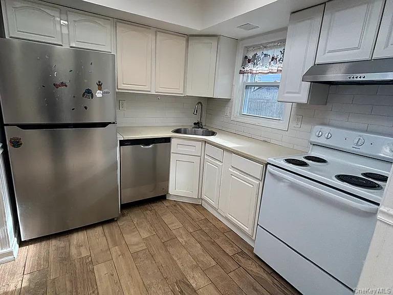 61 Montgomery Avenue Mastic, NY 11950 - Photo 3 of 14 a kitchen with stainless steel appliances a refrigerator sink and cabinets