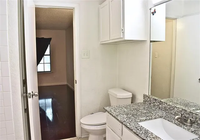 a bathroom with a granite countertop toilet a sink and a mirror