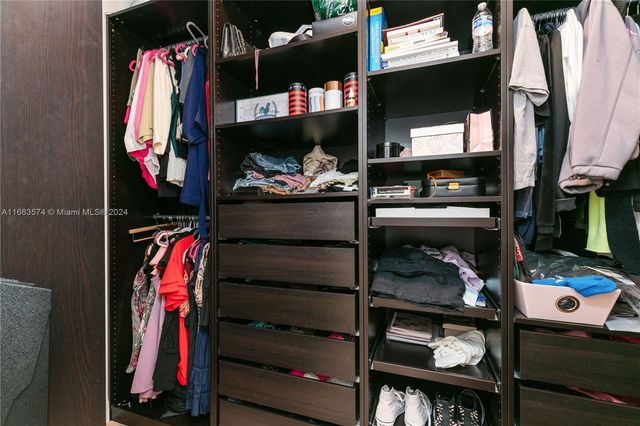 a view of walk in closet with clothes and shoes