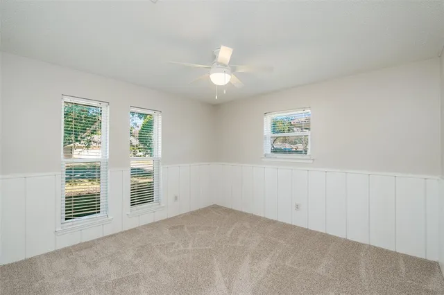 an empty room with windows and ceiling fan