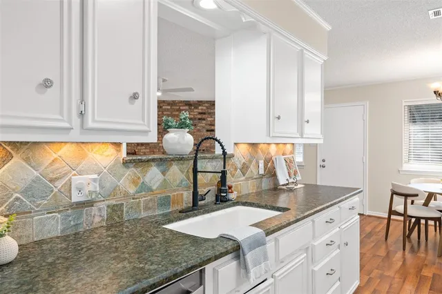 a kitchen with granite countertop a sink and white cabinets