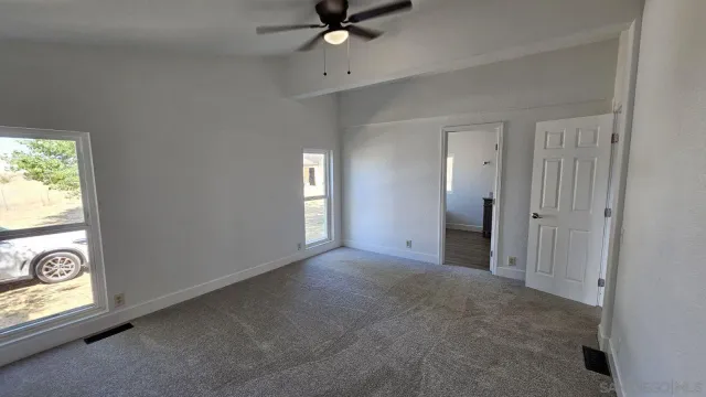 a view of a livingroom with a window and chandelier fan
