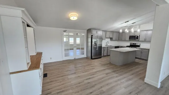 a kitchen with stainless steel appliances a refrigerator a sink dishwasher and a stove with wooden floor