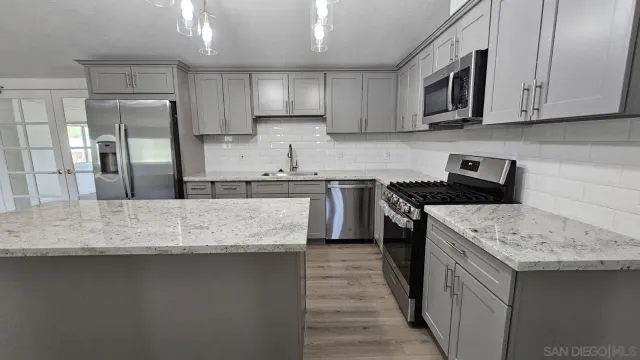 a kitchen with stainless steel appliances granite countertop a sink stove and refrigerator