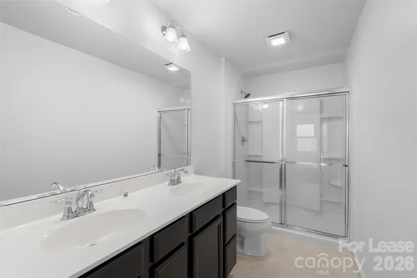 a bathroom with a double vanity sink toilet mirror and shower