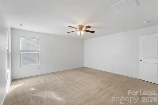 an empty room with chandelier fan and windows