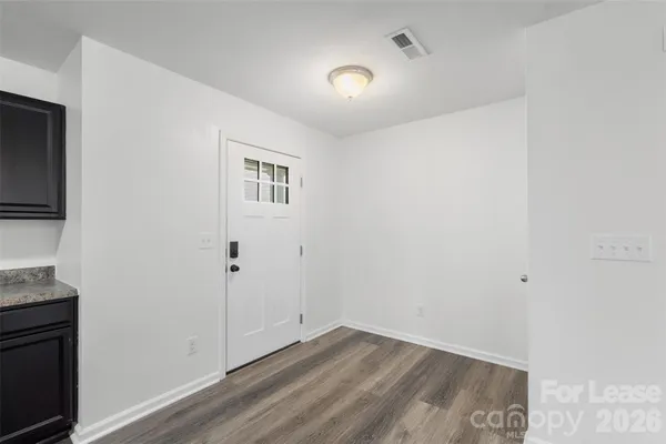 a view of an empty room with wooden floor and a flat screen tv