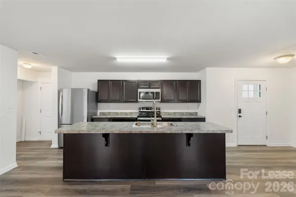 a large kitchen with stainless steel appliances granite countertop a stove a sink and a refrigerator