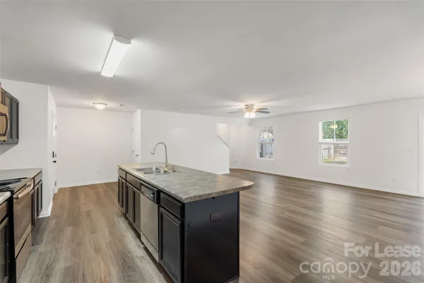 a kitchen with a stove a sink and wooden floor