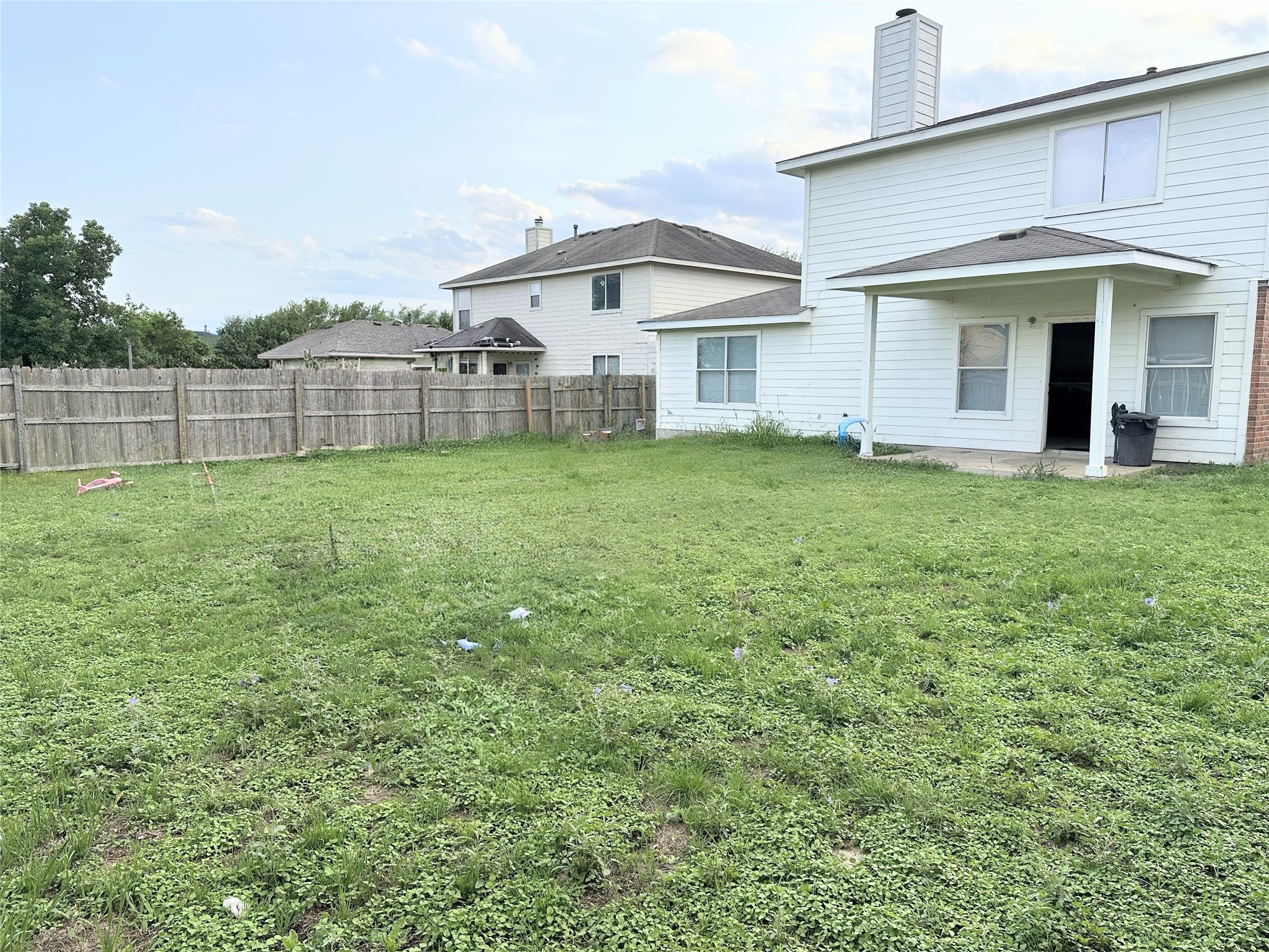 12929 Waynespur Lane Elgin, TX 78621 - Photo 20 of 20 The property features a spacious backyard with a wooden fence and a covered patio area