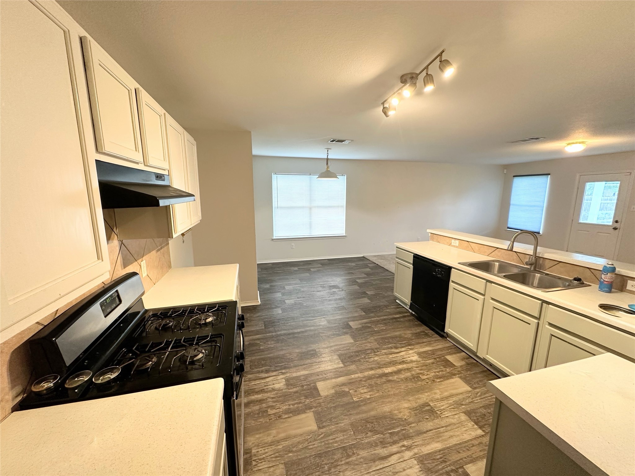 12929 Waynespur Lane Elgin, TX 78621 - Photo 5 of 20 The kitchen features white cabinetry, a black range with an overhead vent, and a double basin stainless steel sink