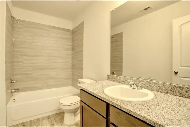 a bathroom with a granite countertop sink toilet and shower