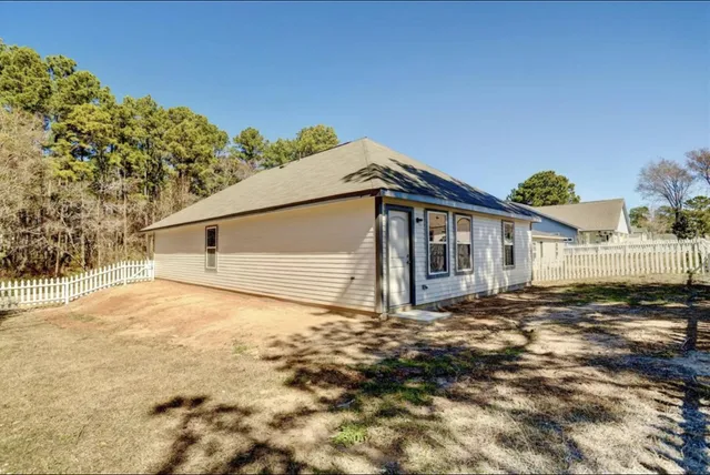 a view of a house with backyard and trees