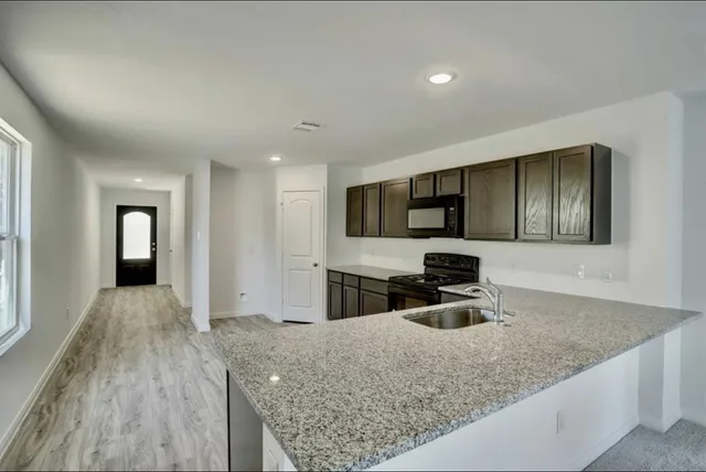 a kitchen with kitchen island granite countertop a sink window and stainless steel appliances