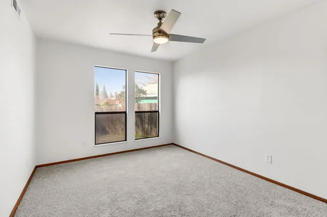 an empty room with windows and fan