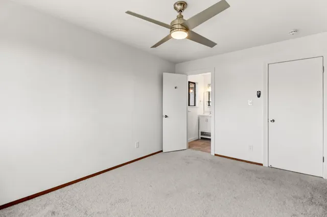 an empty room with closet and a ceiling fan