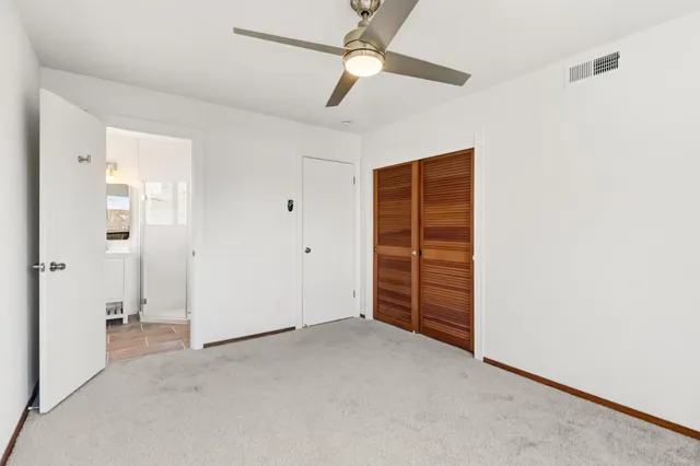 an empty room with closet and a ceiling fan
