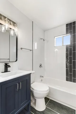 a bathroom with a bathtub shower sink vanity and toilet