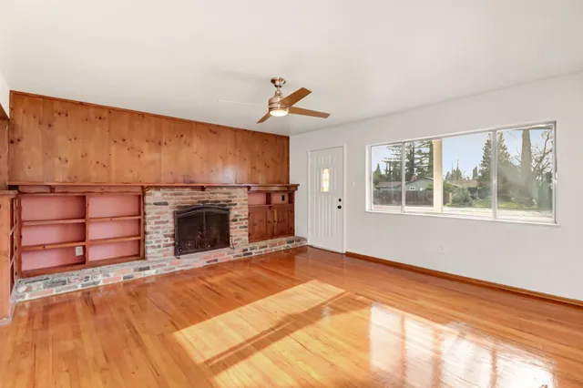 a view of a livingroom with wooden floor fireplace and windows