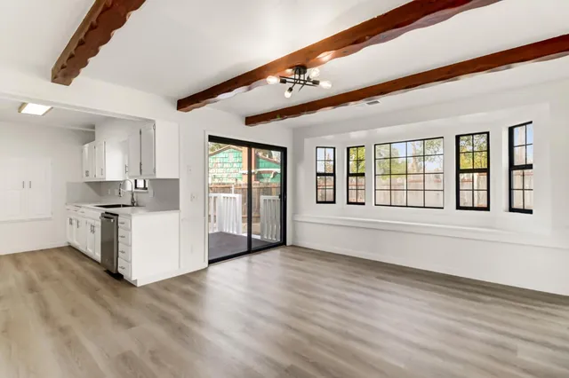 a view of an empty room with kitchen and window