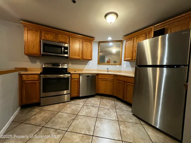 a kitchen with stainless steel appliances granite countertop a refrigerator stove a sink dishwasher and microwave
