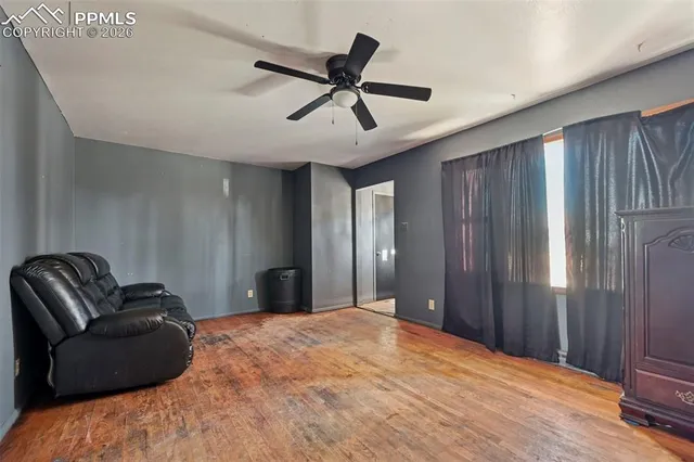 a bedroom with a bed ceiling fan and a wooden floor