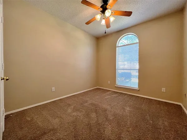 an empty room with windows and fan