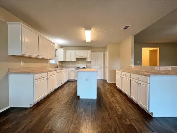 a large kitchen with cabinets wooden floor and stainless steel appliances