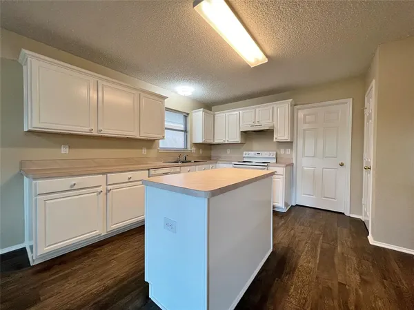 a kitchen with granite countertop a sink cabinets and wooden floor