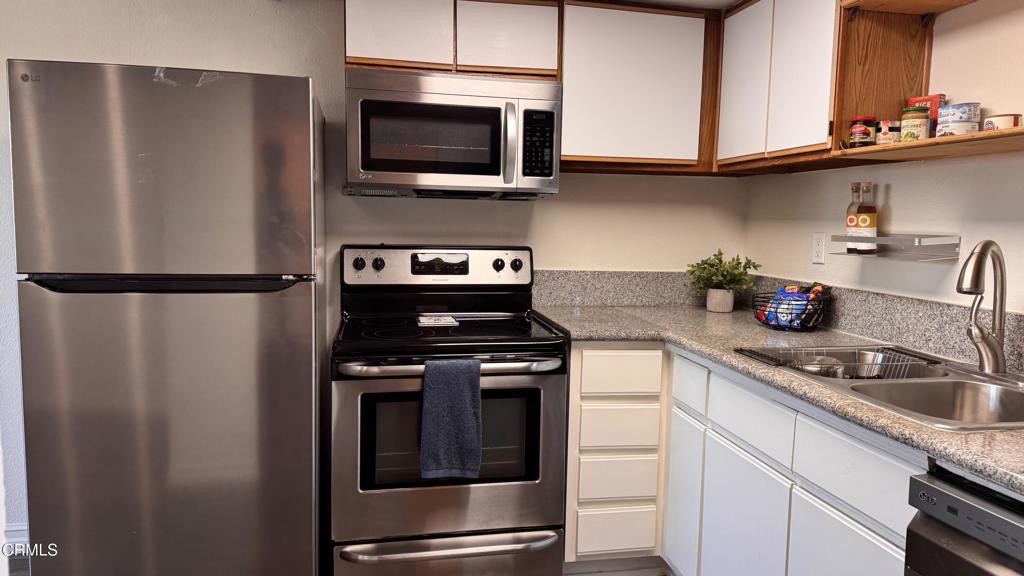 a kitchen with stainless steel appliances granite countertop a refrigerator a stove a sink and cabinets