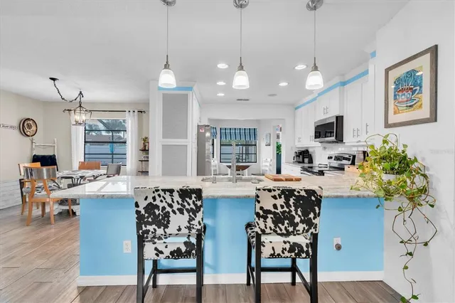 a view of a dining room and livingroom with furniture wooden floor a chandelier
