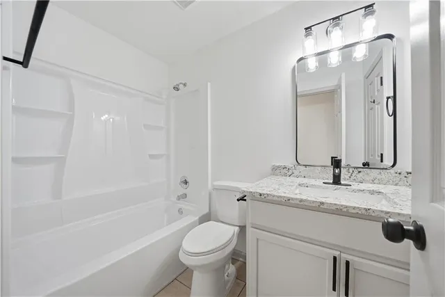 a bathroom with a granite countertop sink toilet mirror and bathtub