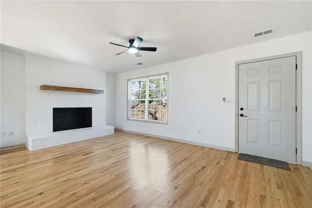 a view of an empty room with glass door and wooden floor