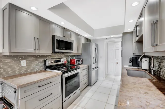 a kitchen with stainless steel appliances granite countertop a stove a sink and a refrigerator
