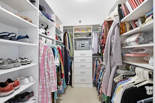 a view of walk in closet with clothes and shoes
