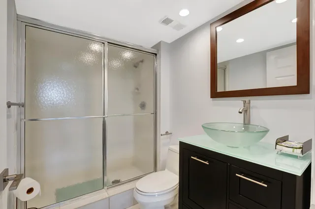 a bathroom with a shower sink vanity mirror and toilet