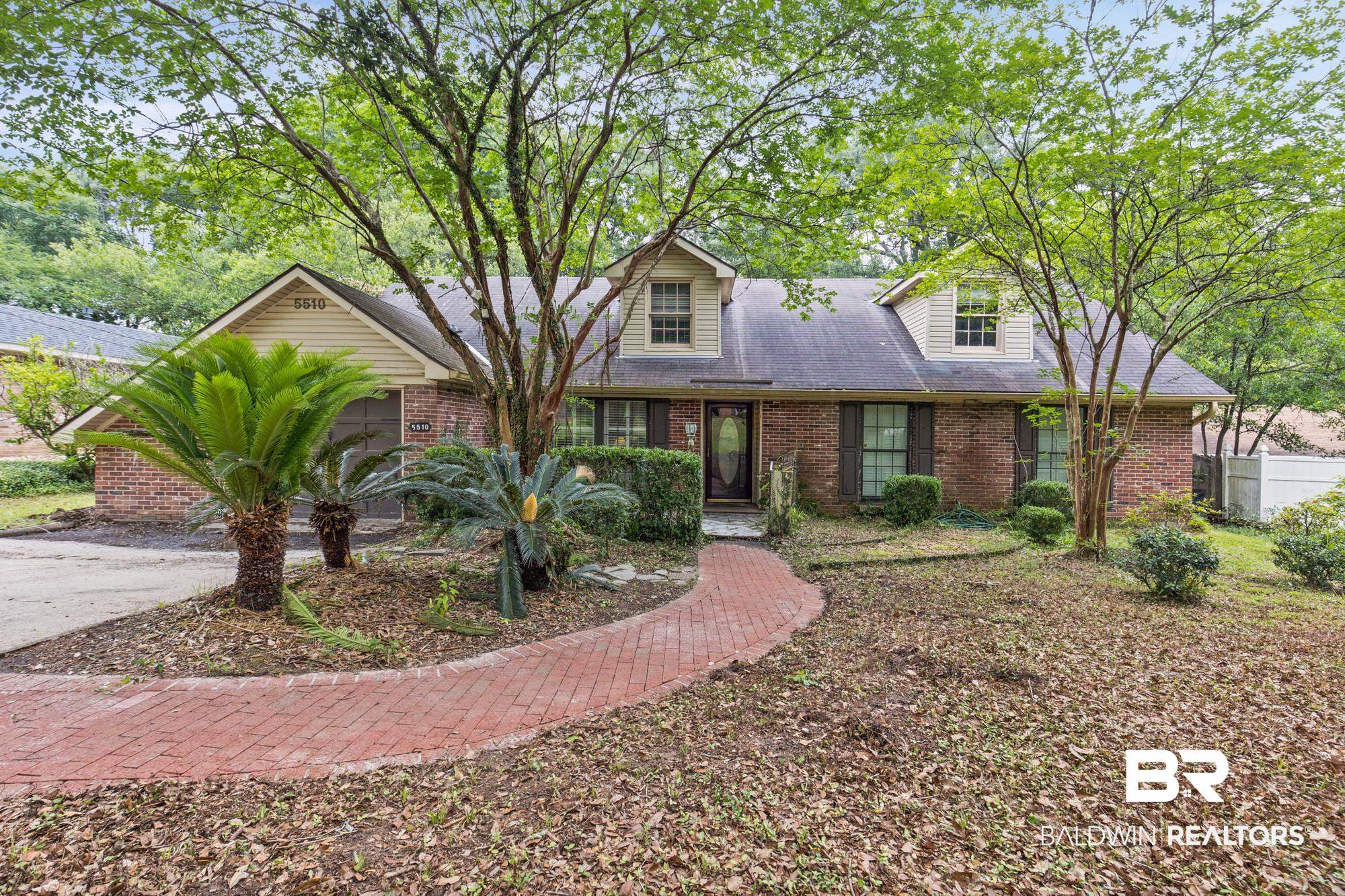 5510 Richmond Road Mobile, AL 36608 - Photo 2 of 21 Brick facade residence featuring a front entry with sidelights, dormer windows, a paved walkway, and mature landscaping
