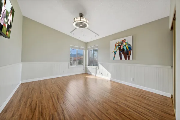 a view of an empty room with wooden floor and ceiling fan