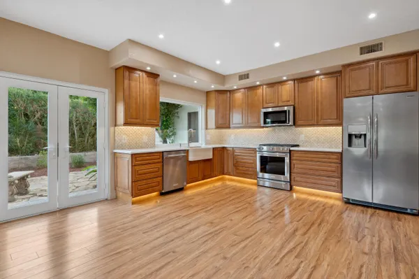 a kitchen with stainless steel appliances a refrigerator a stove top oven and a wooden floors