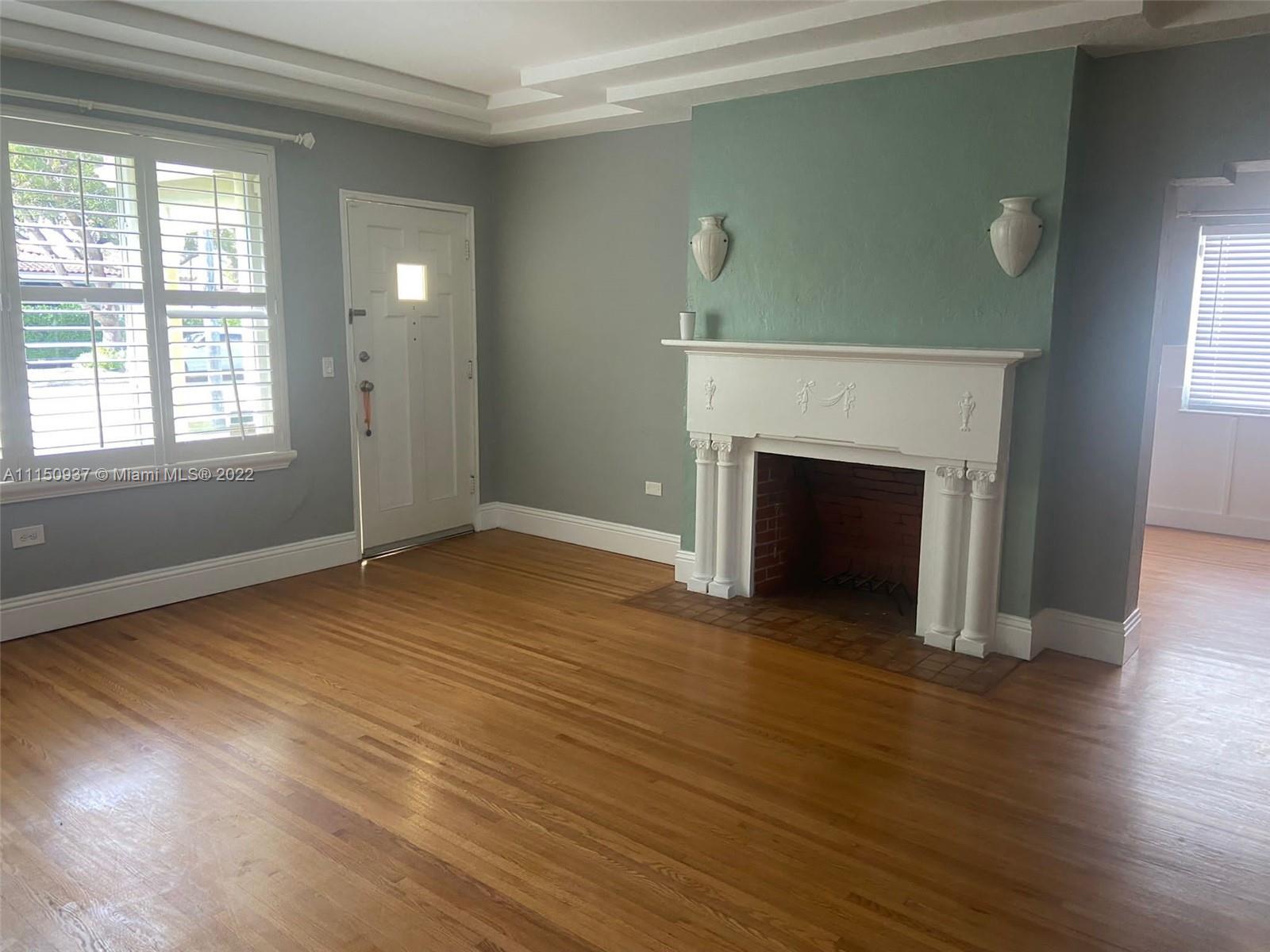 155 Southwest 28th Road Miami, FL 33129 - Photo 4 of 33 an empty room with wooden floor fireplace and windows