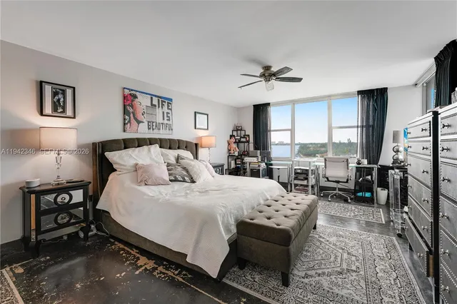 a bedroom with a bed a couch and large windows